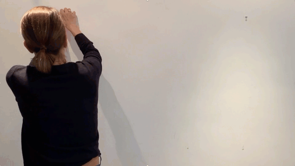 Video zeigt eine Frau von hinten, während sie ein analoges Kanban-Board an der Wand mit farbigem Klebeband und Klebezetteln erstellt