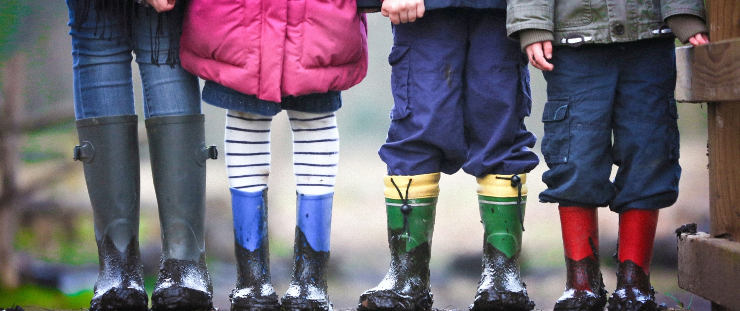 Kinder in Gummistiefeln stehen nebeneinander